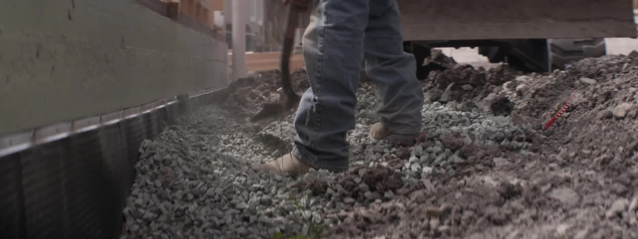 A workers digs in gravel at a construction site