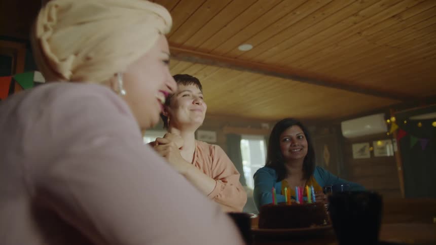 Women laugh next to a birthday cake