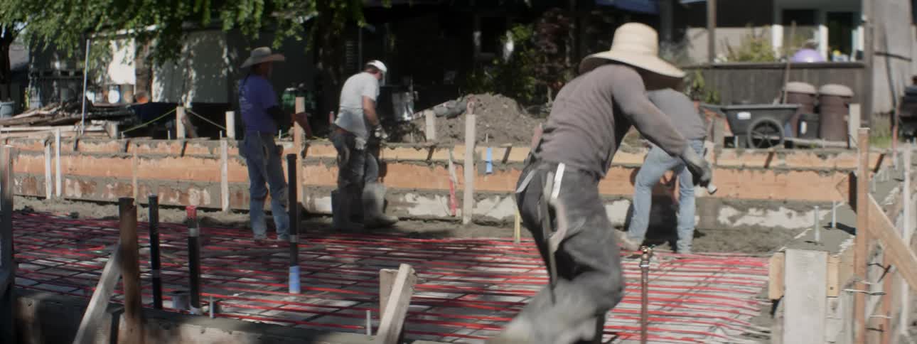 The workers are laying cement together in the yard