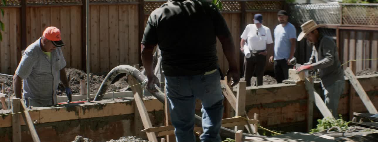 Workers lay concrete at a construction site