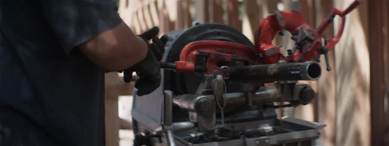 The man is cutting a pipe on a machine