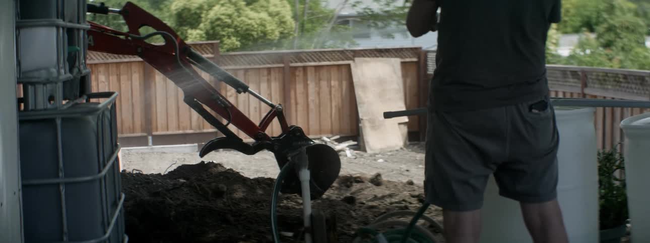 Man uses a hose to spray off a metal object