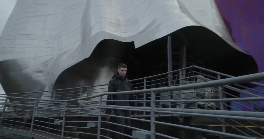 Man walks on a walkway outside of a large building