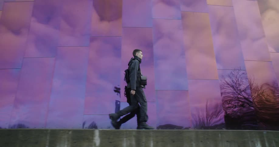The man walks fast past the tall building