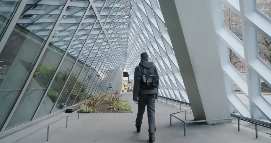 The man moves past the building on a cloudy day