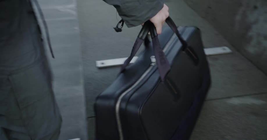 A man carries a leather bag outside