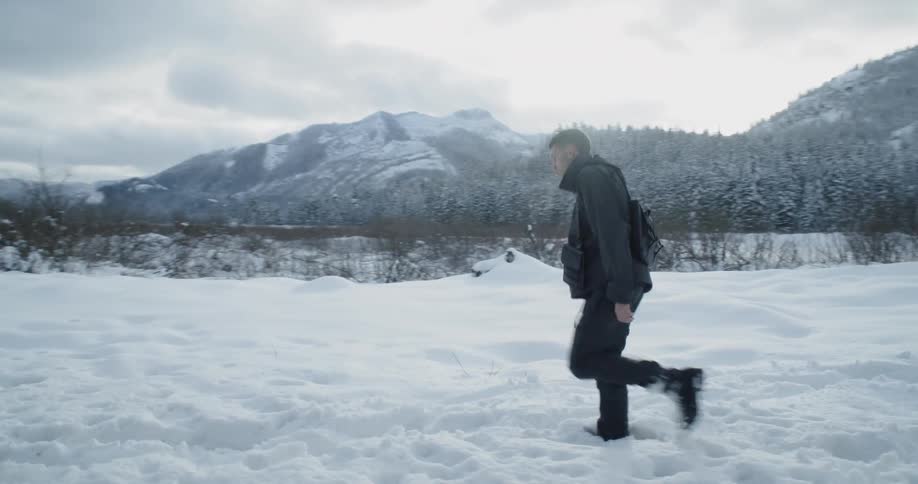 A man hikes over snow near mountains