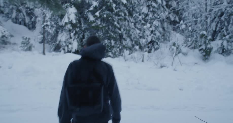 A man hikes in a snowy forest