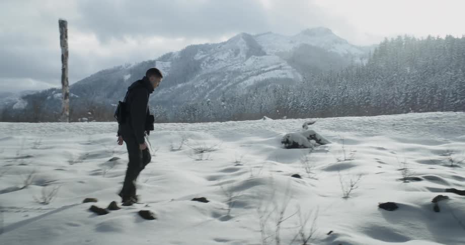 A man hikes over snow near mountains