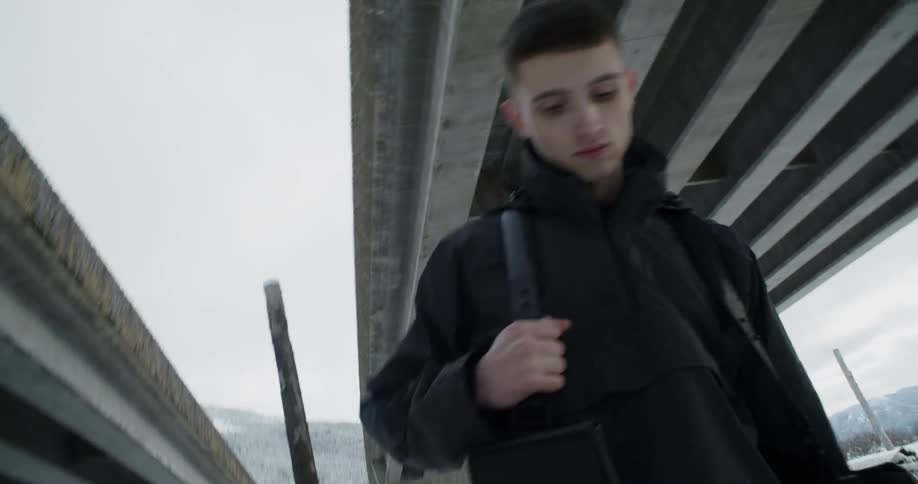 A man stands and poses beneath overpasses