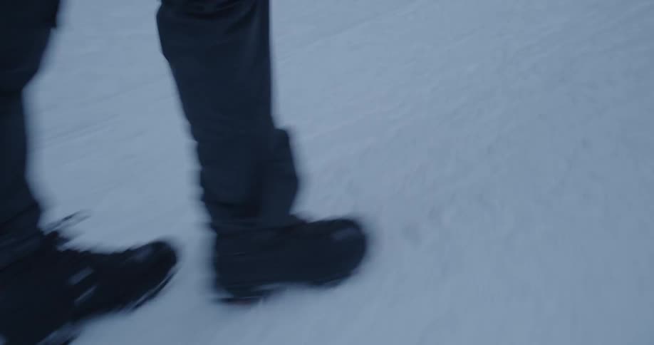 A man wearing boots walks on the snow