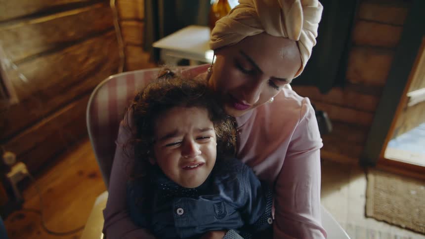 Woman holding a crying child inside