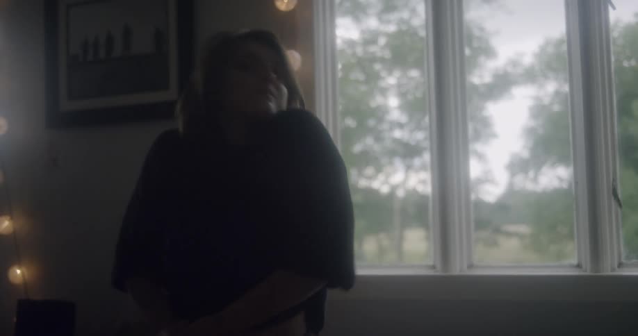 A woman dances in front of a window