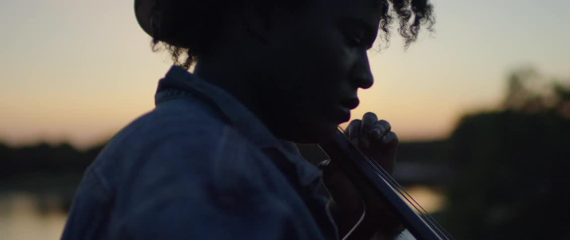 Cellist Playing By Lake At Sunset