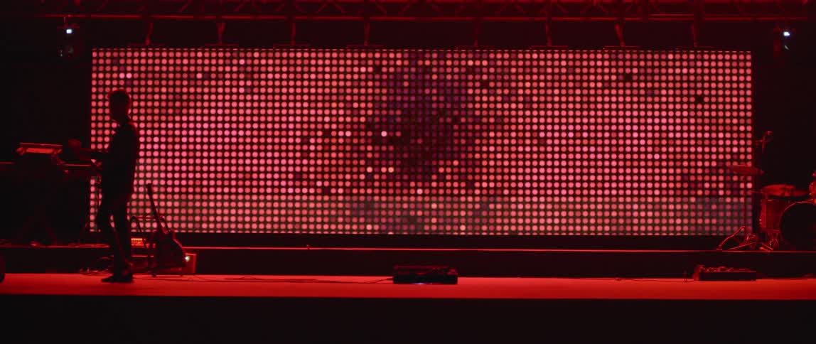 Man stands in front of a large screen of flickering red light