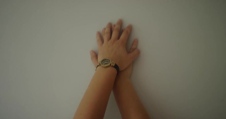 Hand presses against a white wall and one hand covers it