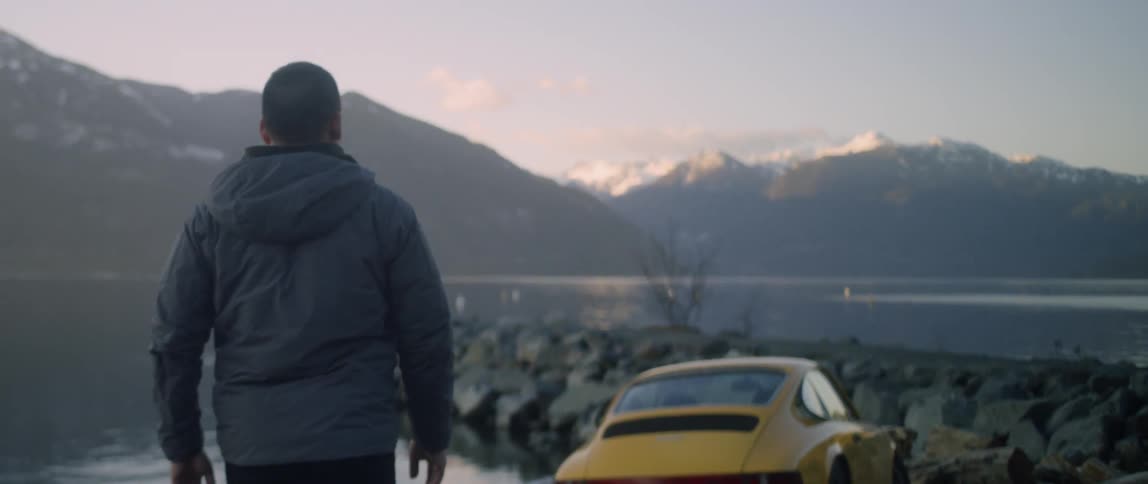 A man walks by a lake at sunset