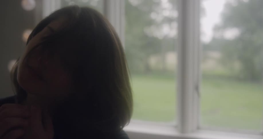 A woman dances by the window
