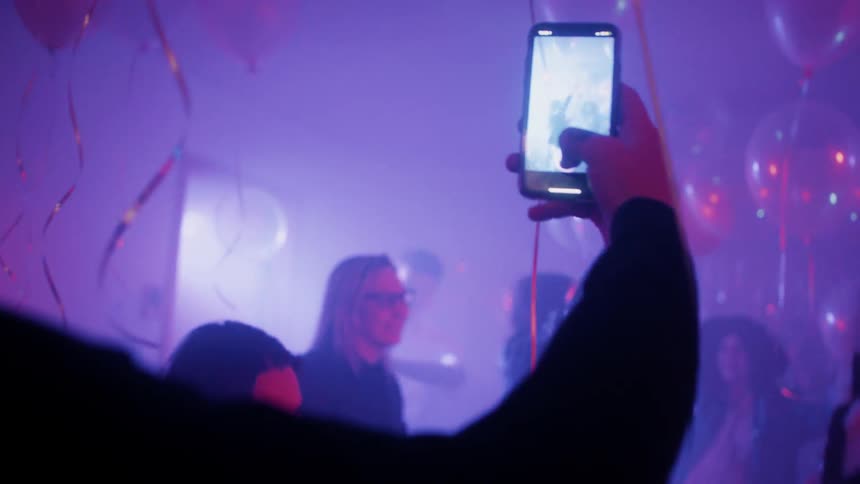 A man films people dancing at a party