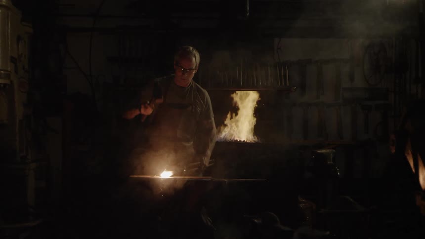 Sparks fly while a blacksmith hammers a piece of hot metal