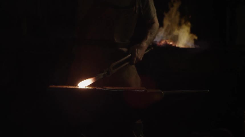 Sparks fly while a blacksmith hammers a piece of hot metal