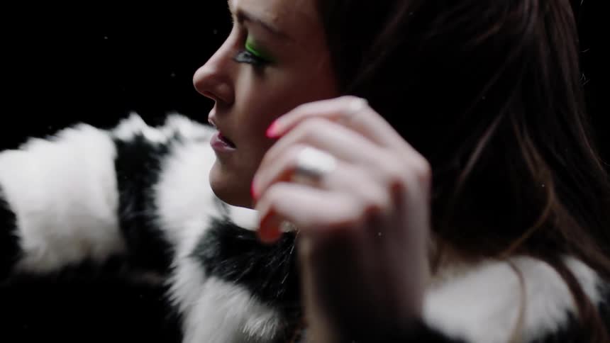 A woman lifts her arms in a fur coat