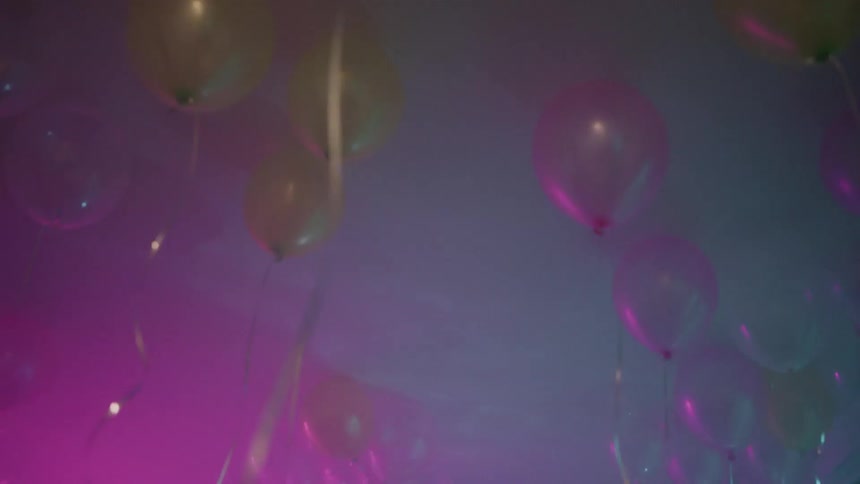 The balloons rise in the room under the flashing lights