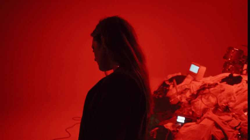 The woman stands by as the man plays drums under the blinking lights