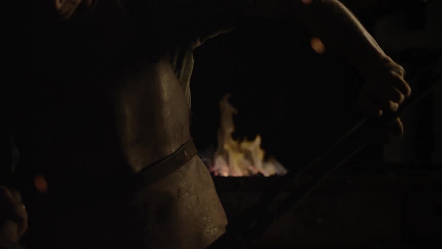 Sparks fly around a blacksmith at work