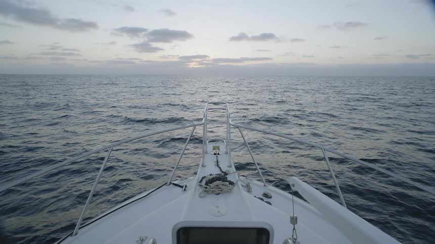 A boat moves in the waters at sunset