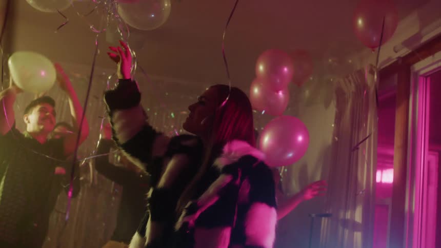 The woman reaches up for the balloons at the party