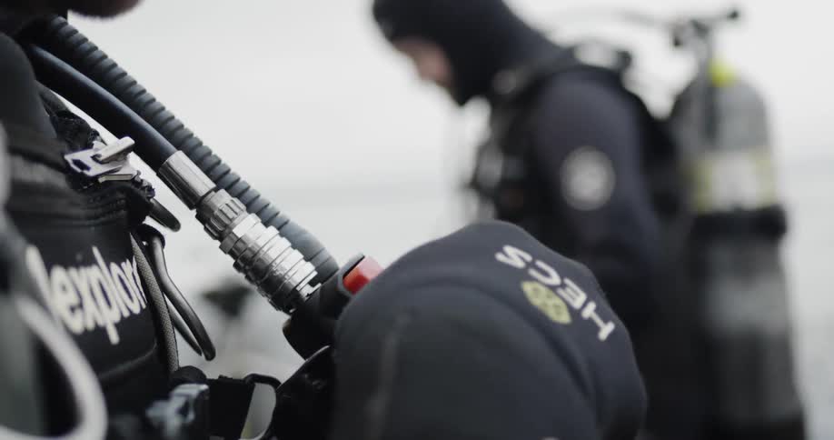 A man checks the regulator on his scuba suit