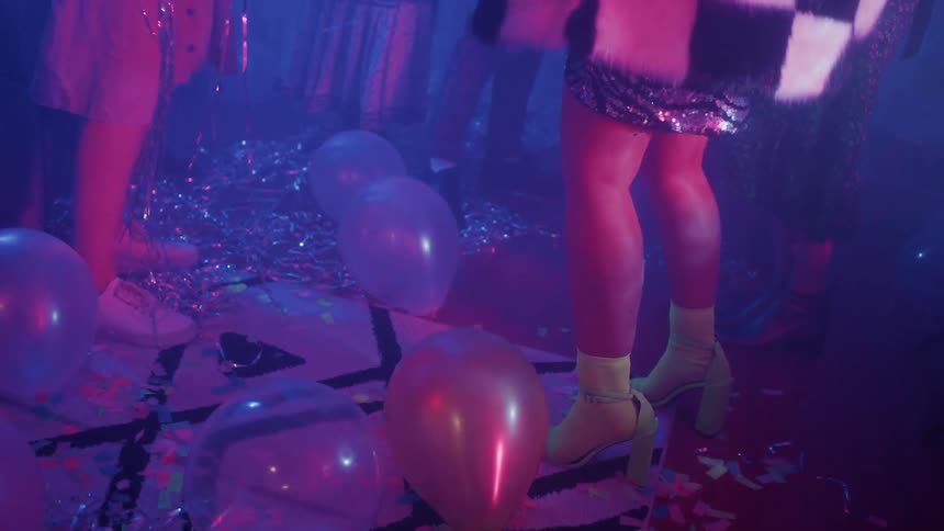 The people dance on the floor covered by balloons