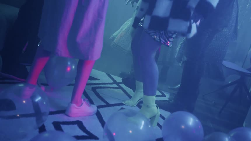 The party goers are dancing around the balloons