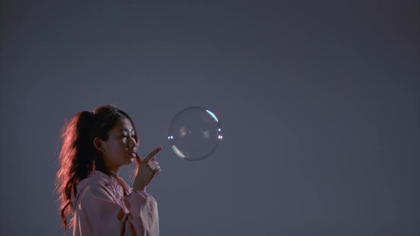A woman puts her finger through a large bubble