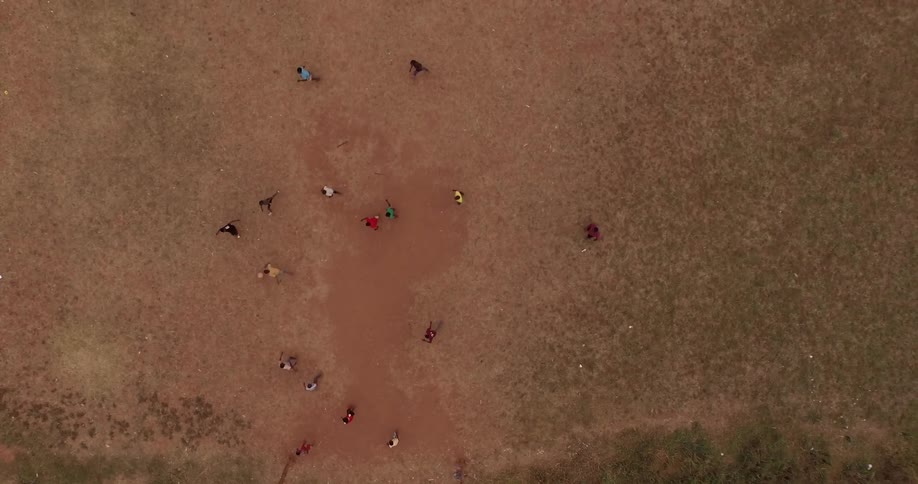 Aerial view of men or boys playing soccer in a bare field of dirt