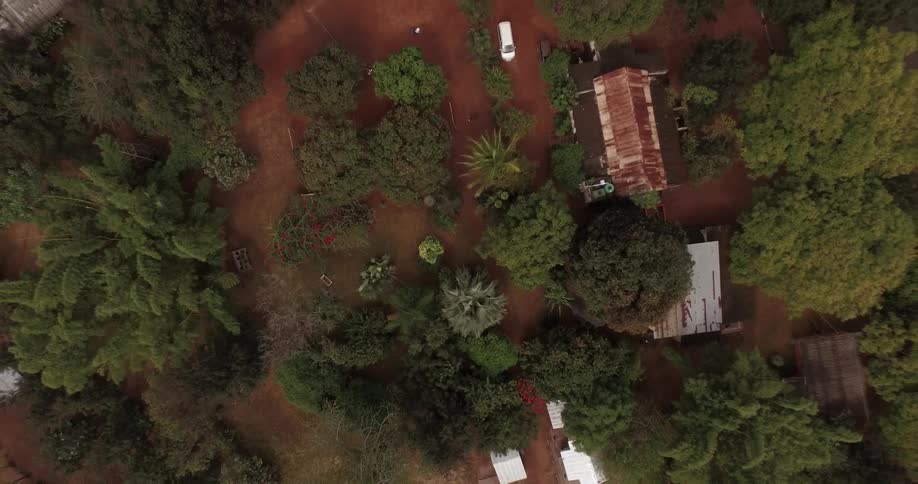 Aerial view of a homestead in a rural area with sparse trees and red-brown dirt
