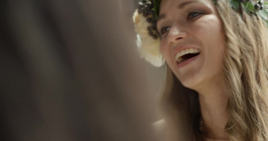 A woman smiling and talking with friends wearing a grass head piece