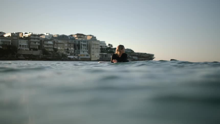 A surfer floats on the water waiting for a wave