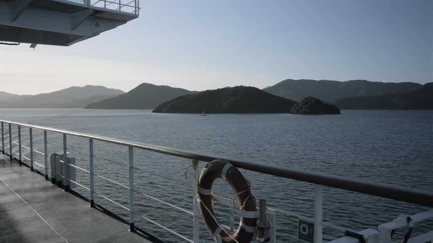A large boat travels on the water near the mountains