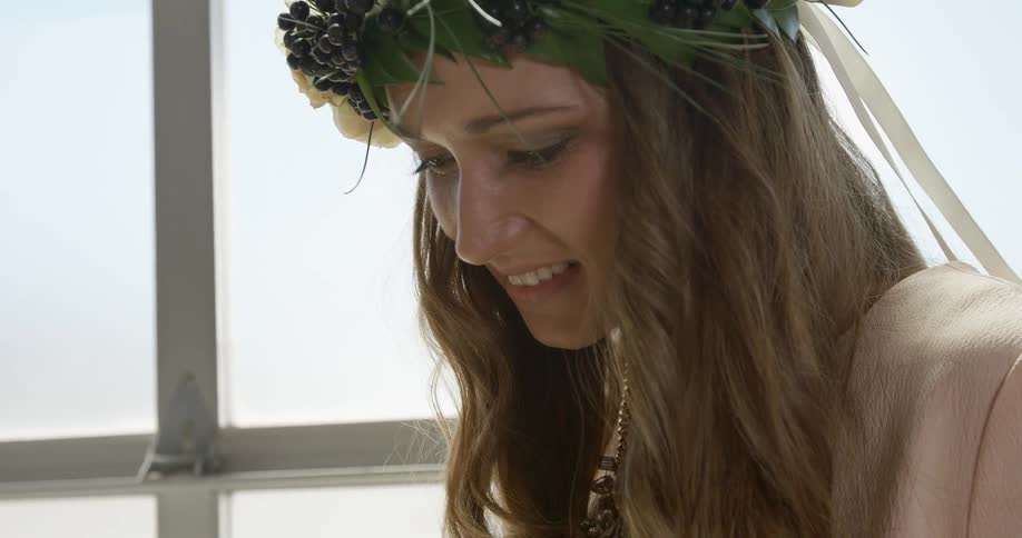 A woman is smiling with a crown of flowers on her head