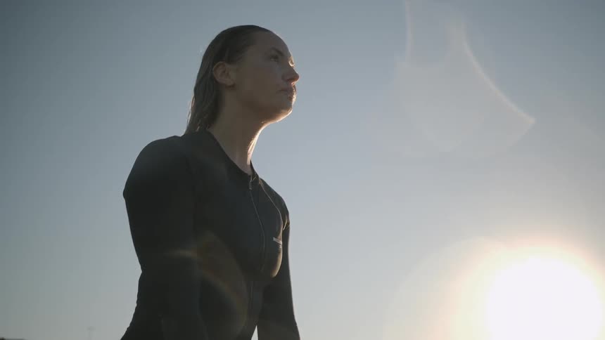 The woman is sitting on her surfboard near the shore