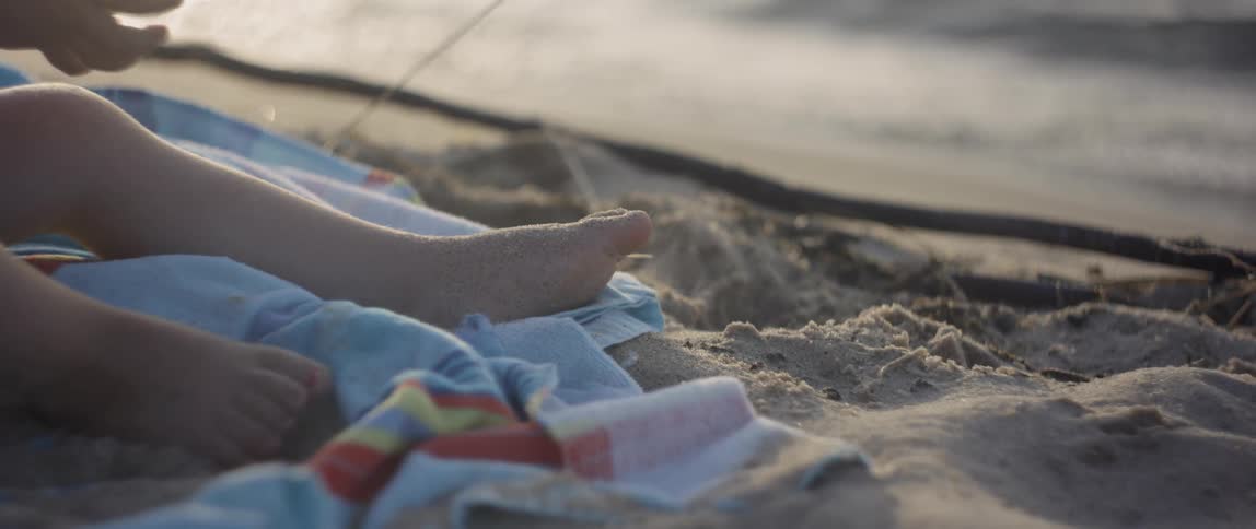 A young girl sits on a towel on the beach