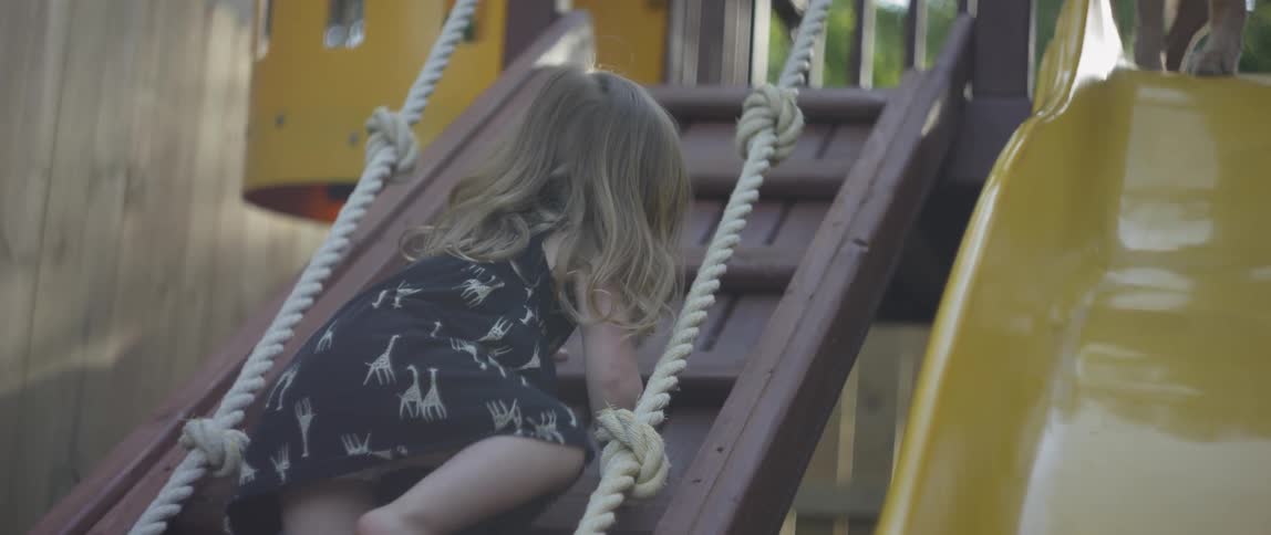 Young girl climbs a ramp to a play house as a dog watches