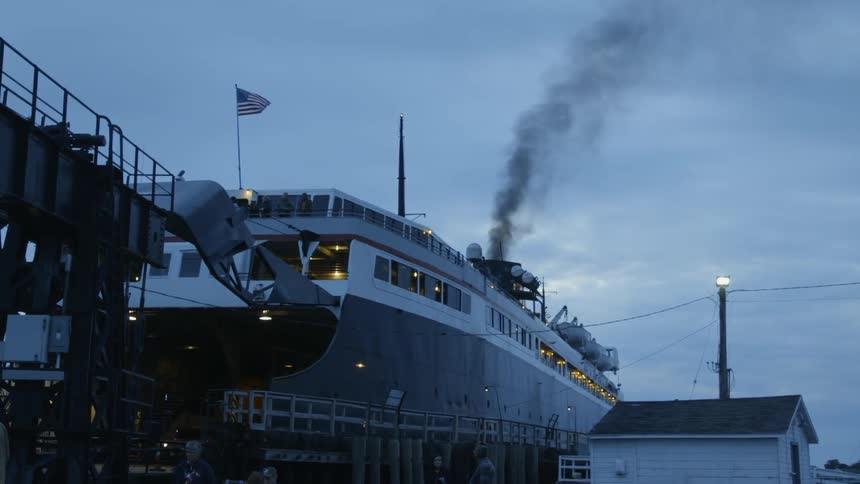 Black smoke billows out of a ferry docked at the pier