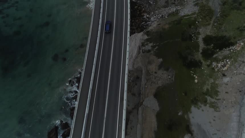 Vehicles travel on a bridge by the shore