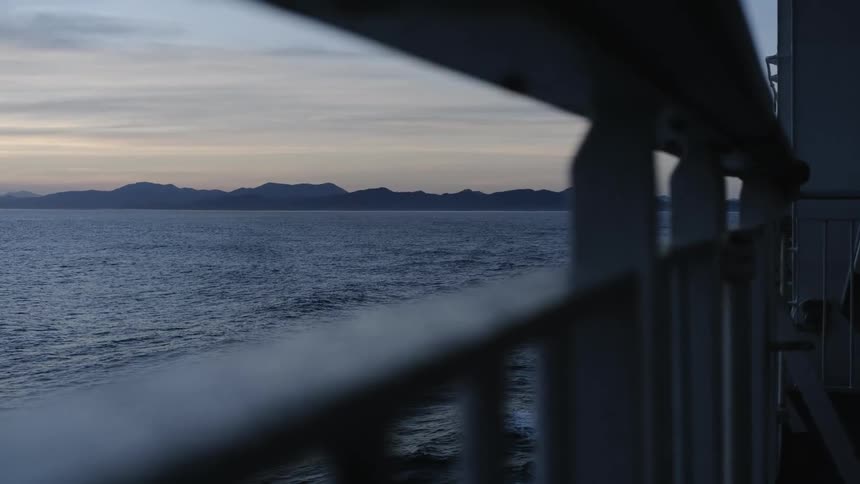 The ship sails away from shore at sunset