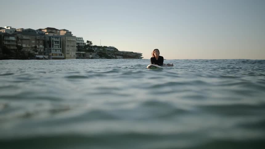 A woman is floating on a surfboard in the water