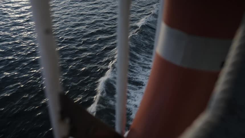 Orange life preserver sits on a boat as it travels through the water