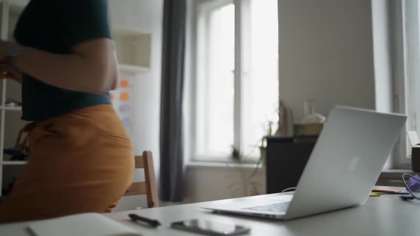 The woman gets up from the laptop and walks off